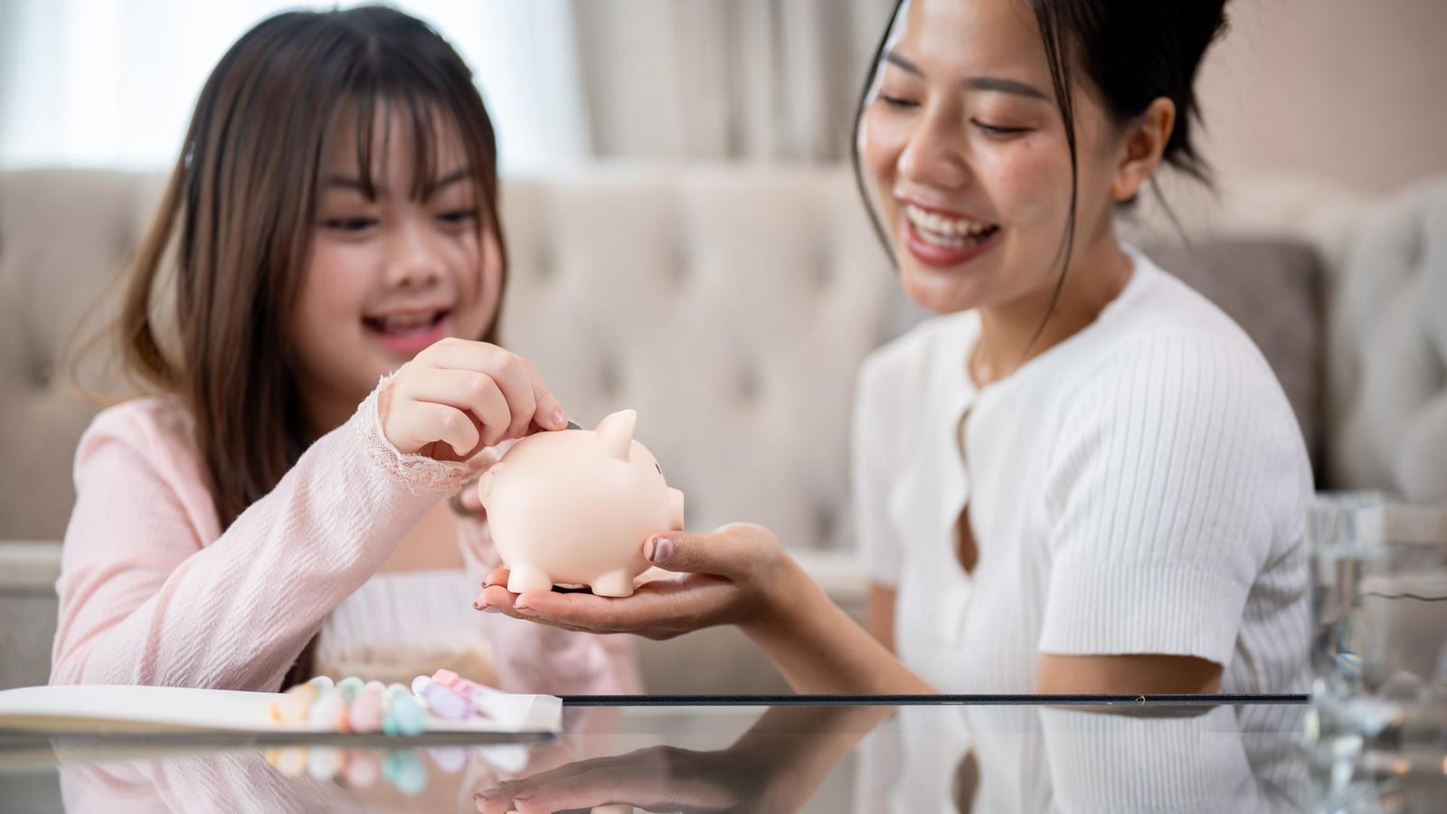 貯金箱にコインを入れる親子。